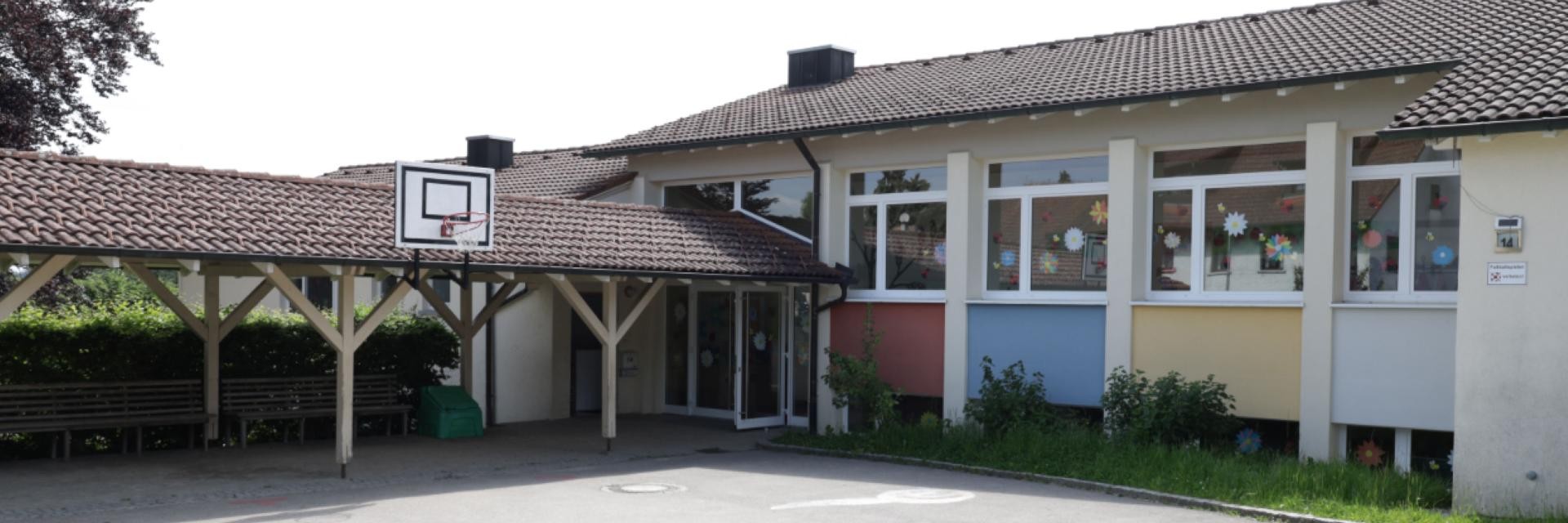 Außenansicht einer Grundschule, die einen Basketballplatz zeigt, ideal für sportliche Betätigung und Freizeitaktivitäten.
